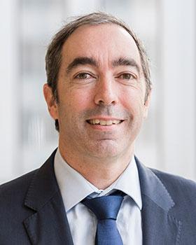 Man in a dark blue suit smiles at the camera