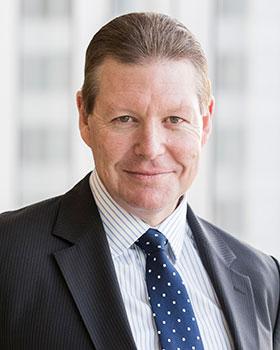 image of Michael Ward wearing a black suit and blue tie