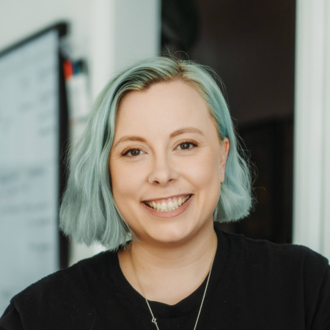 Headshot of a smiling person in a dark top